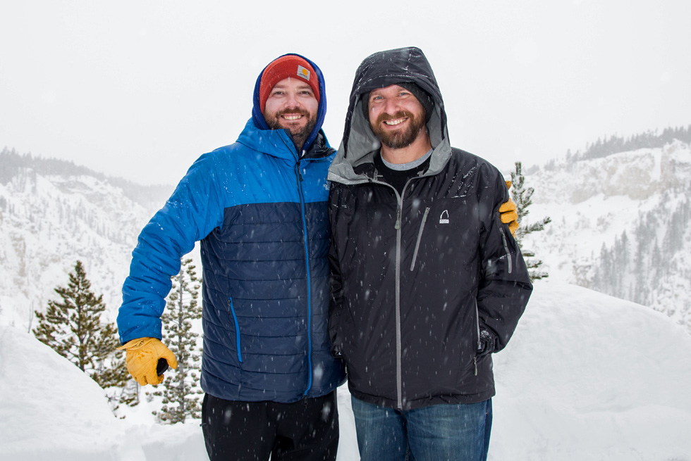 Two Yellowstone snowcoach passengers take a photo by the Grand Canyon of the Yellowstone.