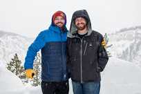 Two Yellowstone snowcoach passengers take a photo by the Grand Canyon of the Yellowstone.